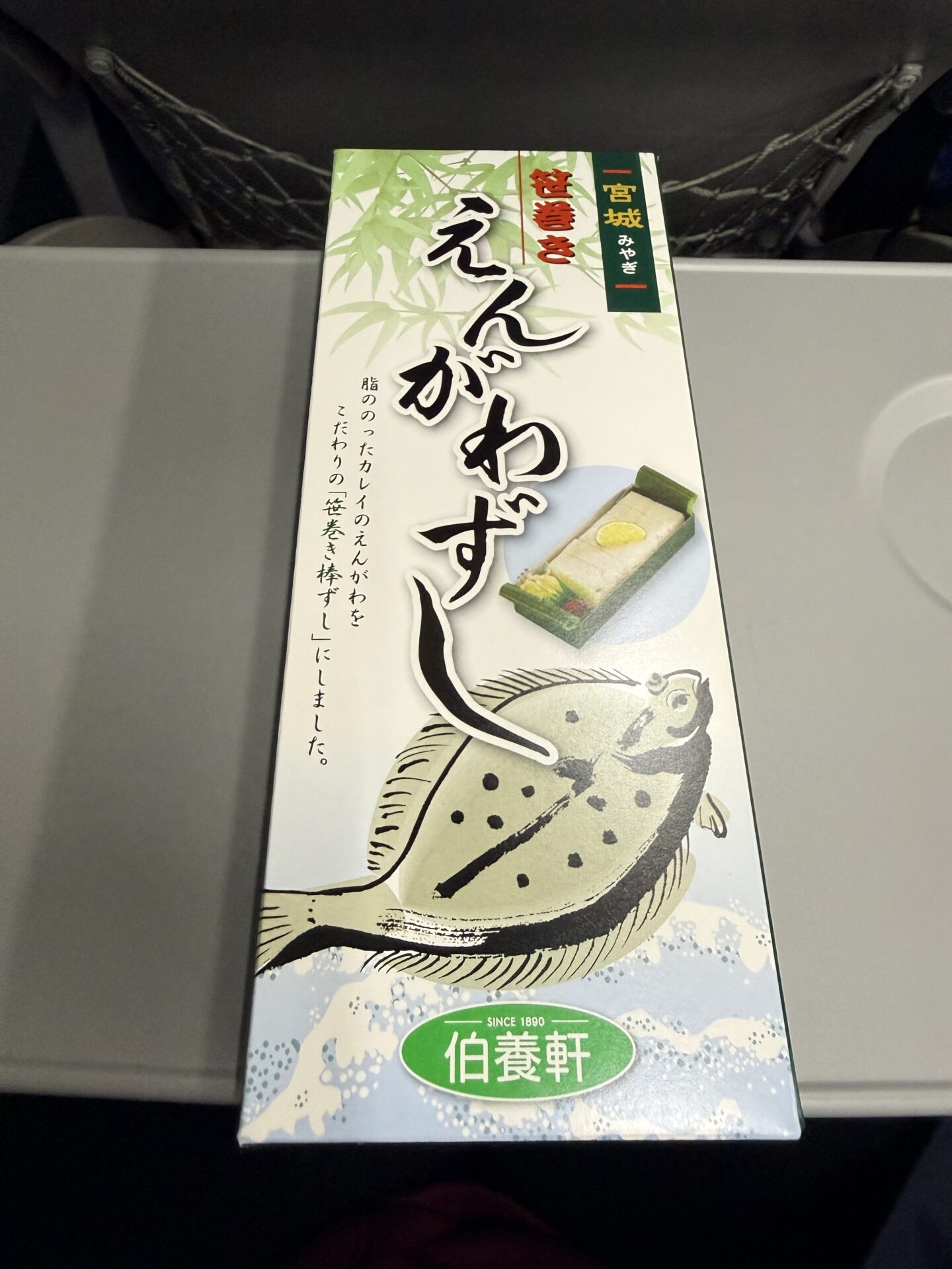 笹巻きえんがわずしのパッケージ正面。緑の笹デザインに「宮城」「伯養軒」のロゴ、カレイのイラストが映える縦長パッケージ