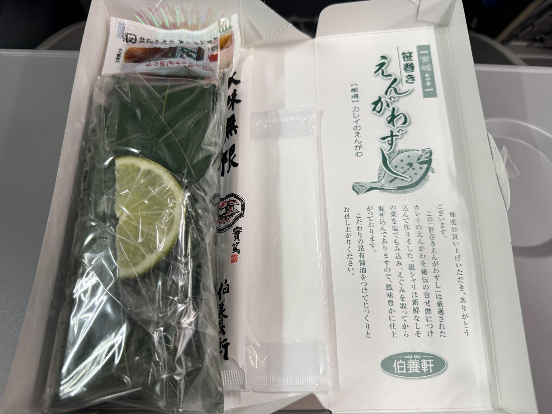 笹巻きえんがわずしのパッケージ。笹の葉で包まれた押し寿司にレモンが添えられた上品なデザイン