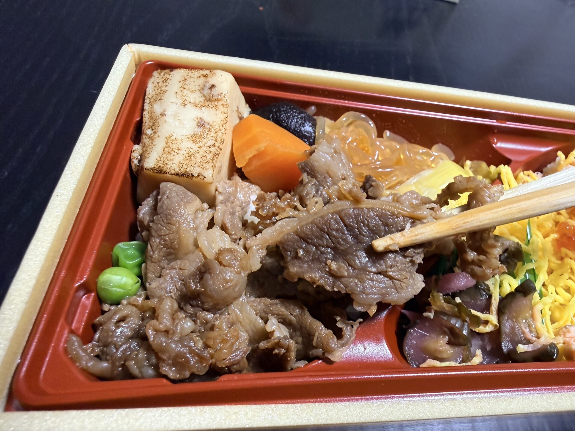 米沢牛すきやきを箸で持ち上げた瞬間。冷めても柔らかく、艶やかな甘辛タレが絡んでいる