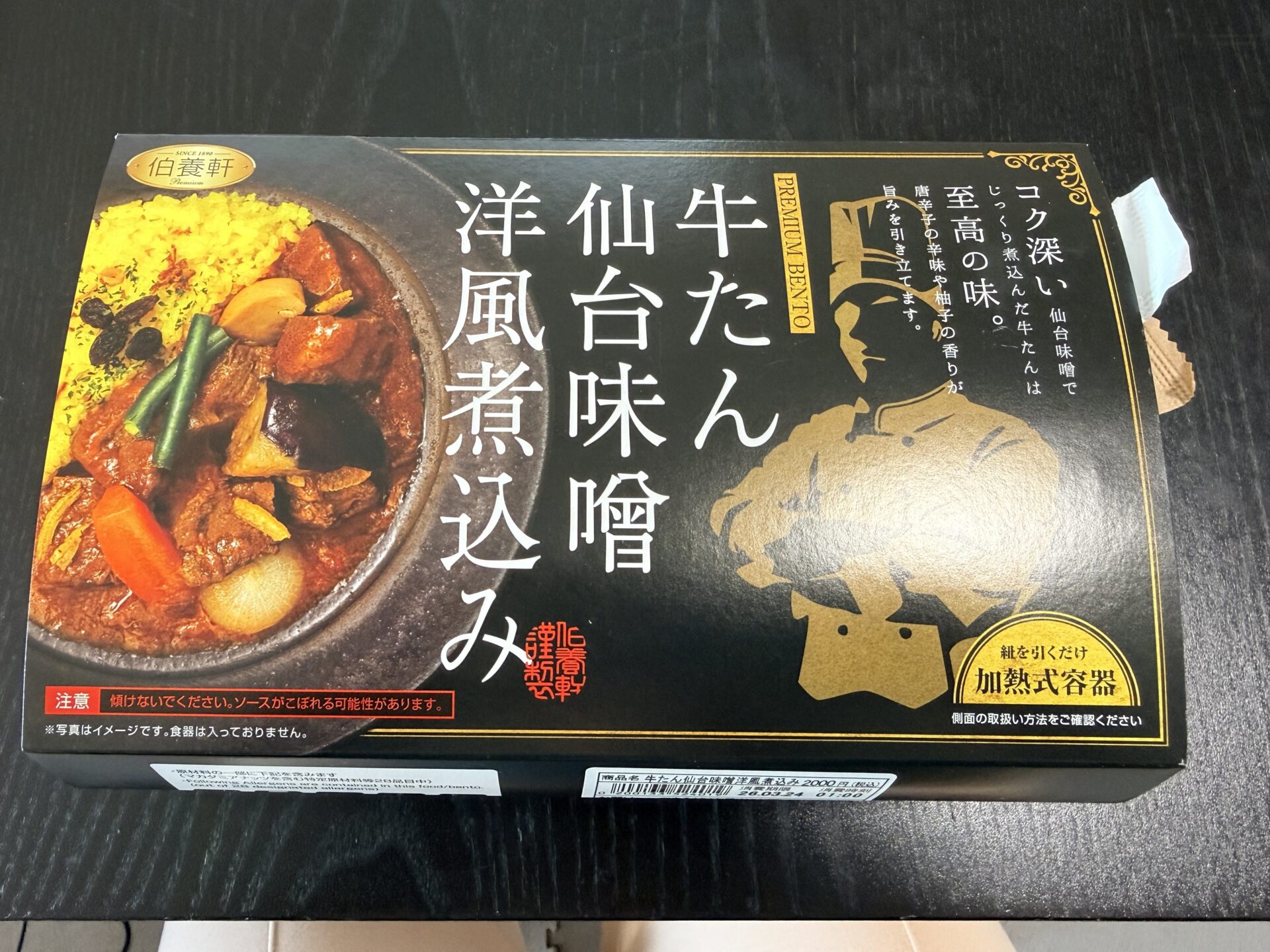 牛たん仙台味噌洋風煮込みのパッケージ。黒×金の重厚感あるデザインに料理人を思わせる金色のシルエットと「至高の味」のキャッチコピー