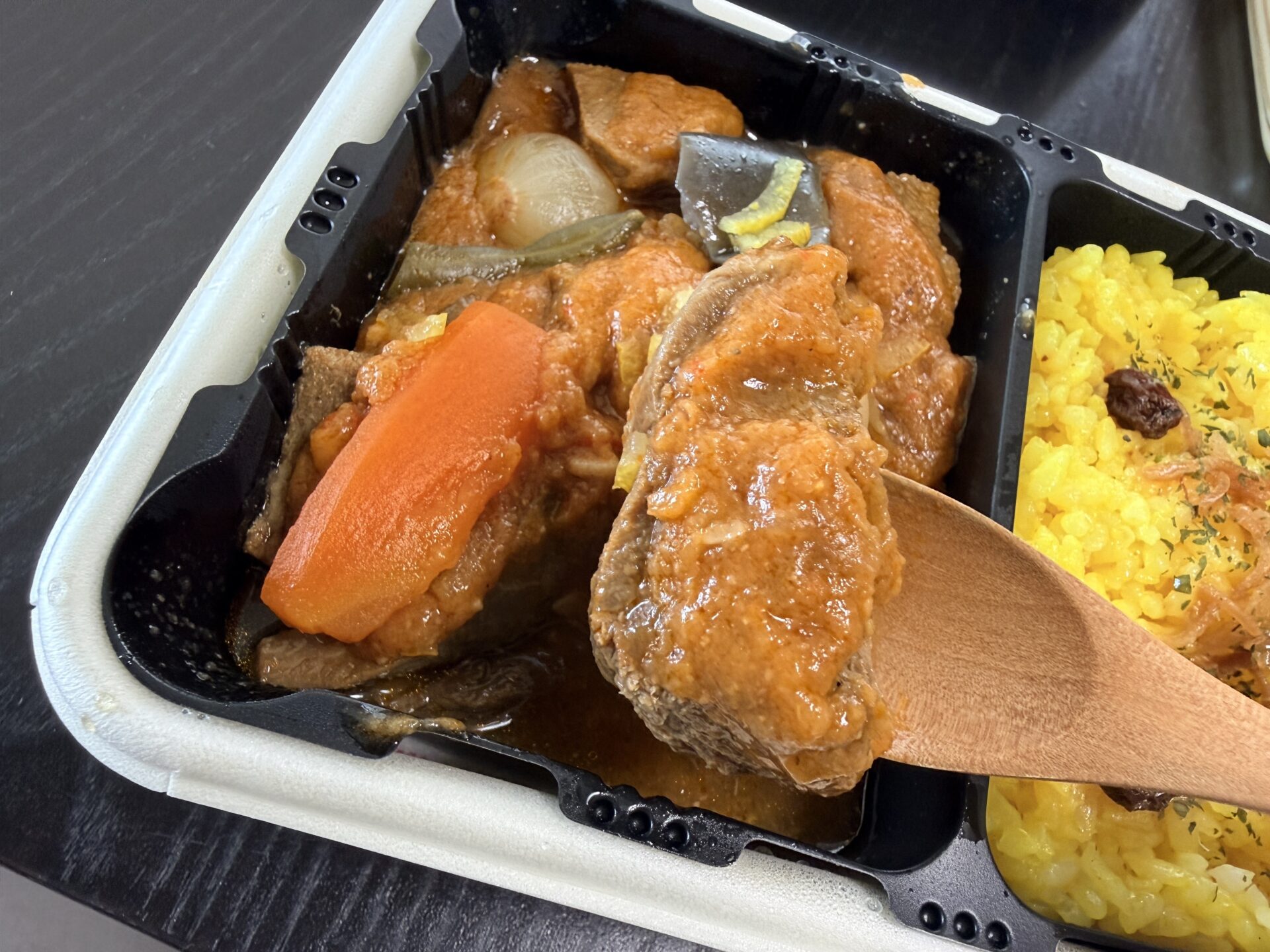 木のスプーンで持ち上げた大ぶり牛たん。仙台味噌の煮込みダレをまとった厚切り牛たんの存在感が圧倒的