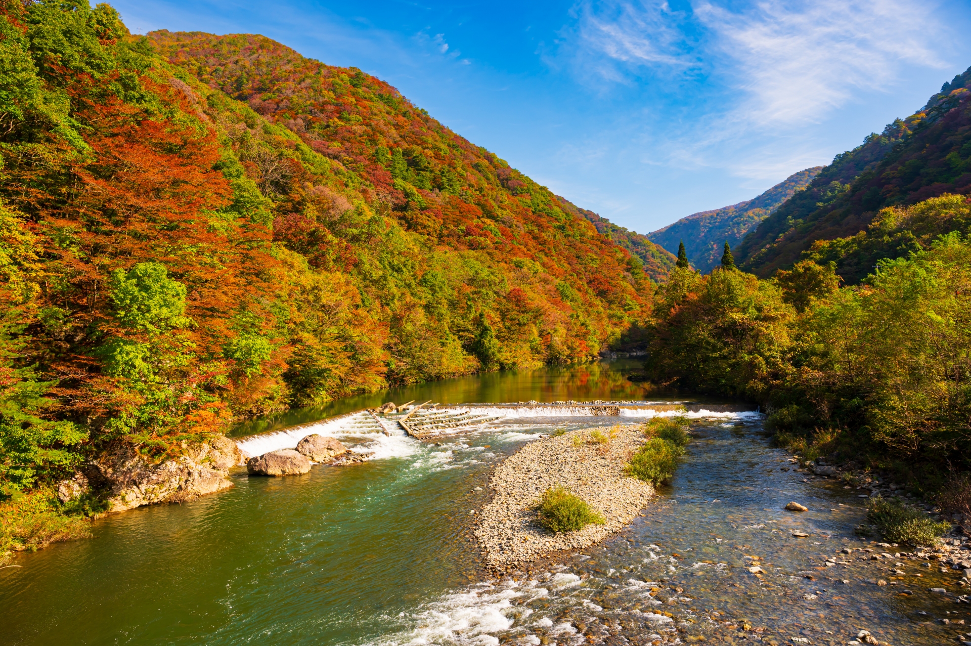 紅葉の山に挟まれた渓谷の流れ