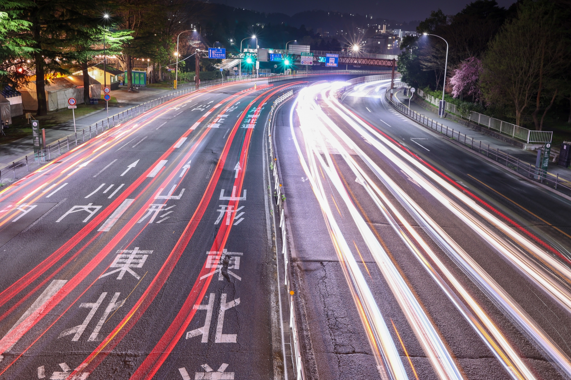 夜の高速道路。路面に「山形」「東北」の行き先表示が見える